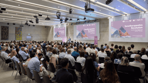 Panoramic view of the packed Aula Magna at USI during the ‘Senotherapeutics Revolution’ forum, with the speaker on stage and double projection of the event visuals in the background.