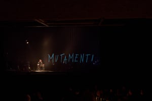 Telmo Pievani durante lo spettacolo Nomadic e la parola MUTAMENTI proiettata