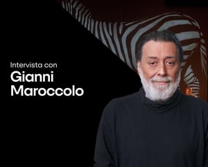 Ritratto di Gianni Maroccolo accanto al testo “Intervista con Gianni Maroccolo – Nomadic, Canto per la biodiversità.” Indossa un dolcevita nero su uno sfondo scuro con un motivo stilizzato di zebra. Il logo di IBSA Foundation for scientific research compare in basso.