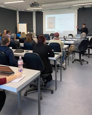 Una docente in maglia fucsia indica una mappa geografica proiettata su uno schermo, durante una lezione sulle terre indigene in Brasile.